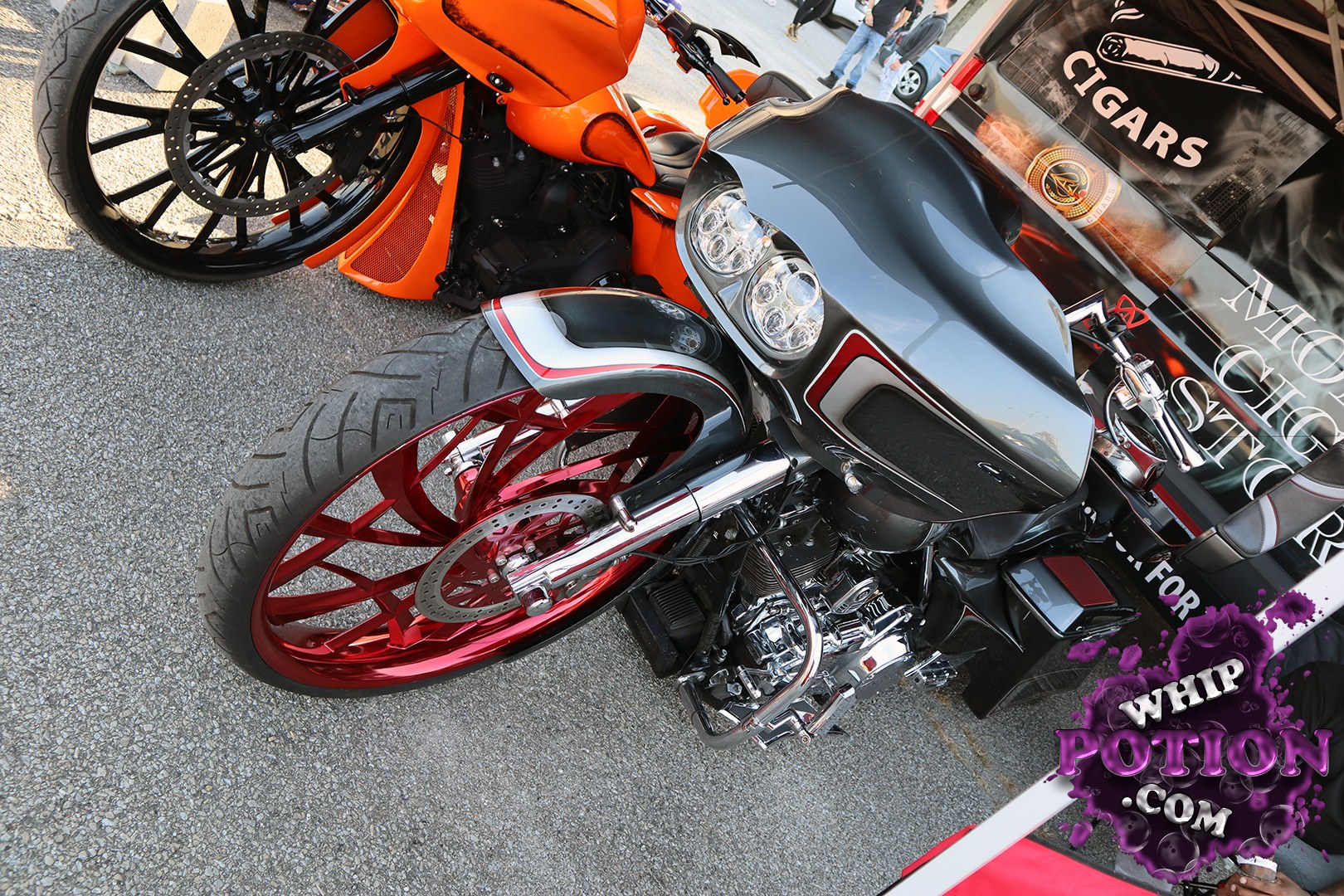 This custom touring-style motorcycle goes all in on show-bike drama, with a deep black-and-orange finish, oversized red billet wheels, and a stretched front end that gives it serious presence. The twin headlight fairing, chrome V-twin motor, and low-slung seat tie the build together cleanly, while the matching details keep it looking sharp from nose to tail.