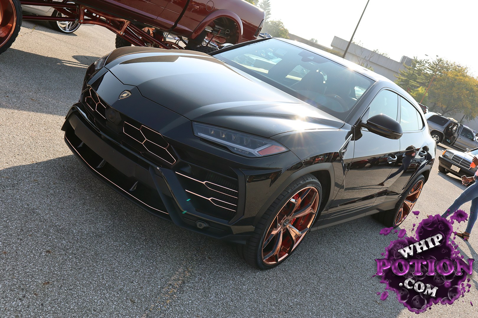 A Lamborghini Urus gets the custom treatment here, finished in deep gloss black with copper-toned multi-spoke wheels that give it a real show-floor presence. The sharp LED lighting, aggressive front fascia, and those wide hips make the SUV look planted, while the clean, monochrome build keeps the whole package sleek and purposeful.