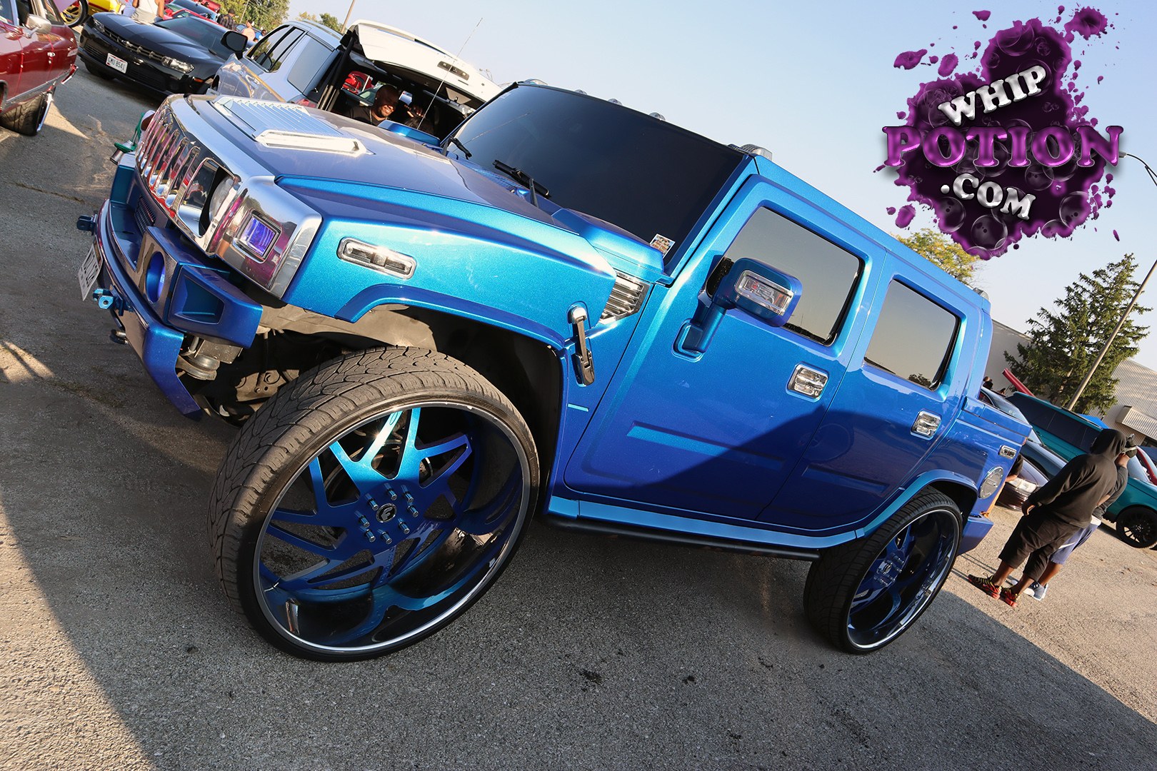 This Hummer H2 gets the full custom treatment with a deep metallic blue finish, a chrome grille, and huge color-matched big wheels tucked under the fenders. The stance is tall and aggressive rather than lowered, and the clean, monochrome look carries through the mirrors, trim, and body kit for a loud but cohesive street build.