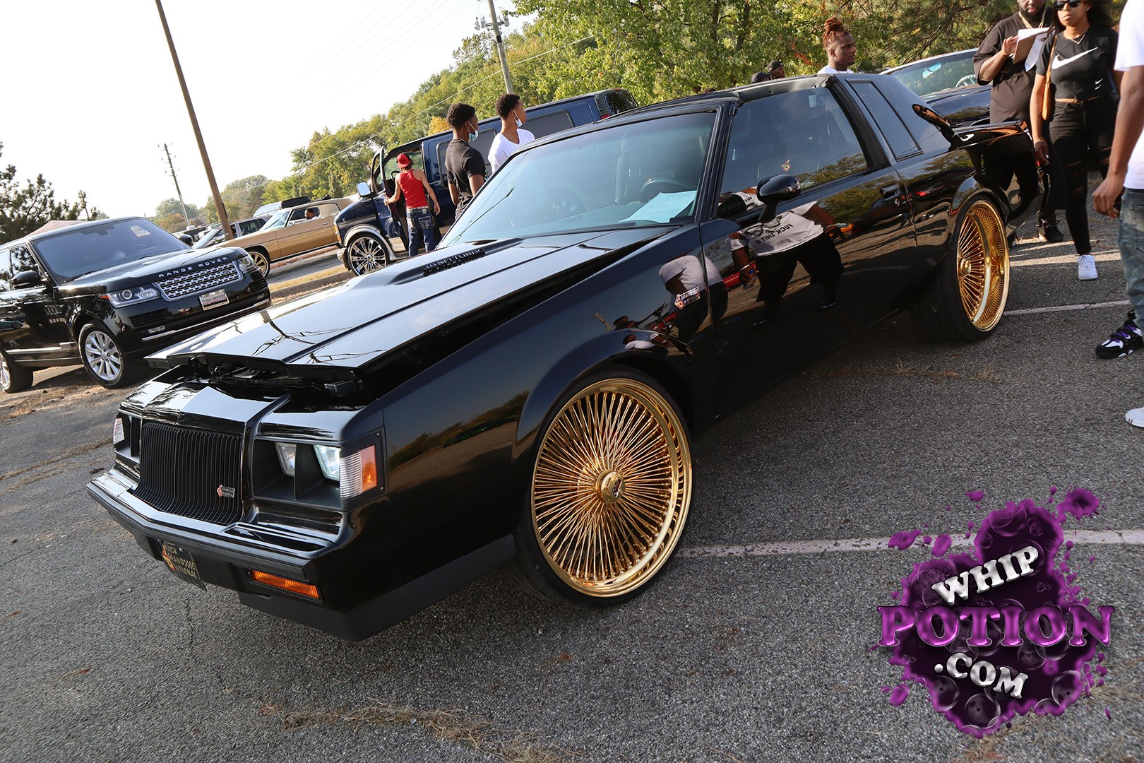 This black Buick Regal coupe has the kind of presence only a proper G-body can pull off, with a shaved, monochrome look, a raised hood, and massive gold wire wheels tucked under the fenders. The clean bodywork and glossy finish keep it classy, while the stance and wheel choice give it full custom-car attitude without overdoing it.