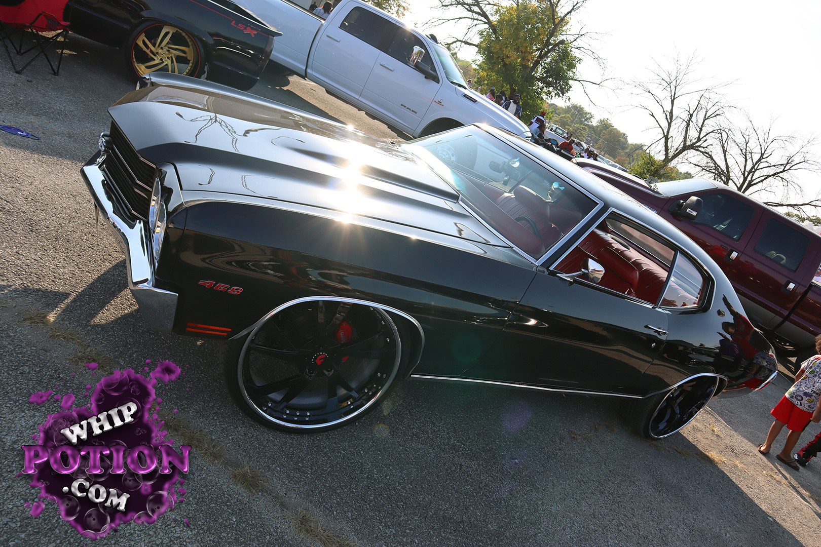 This black Chevrolet Chevelle 2-door wears a deep gloss finish, a cowl-induction hood, and huge polished custom wheels that fill the wells just right. The red interior pops through the glass, while the clean chrome trim and 468 badging give it that old-school muscle presence with a serious modern stance.