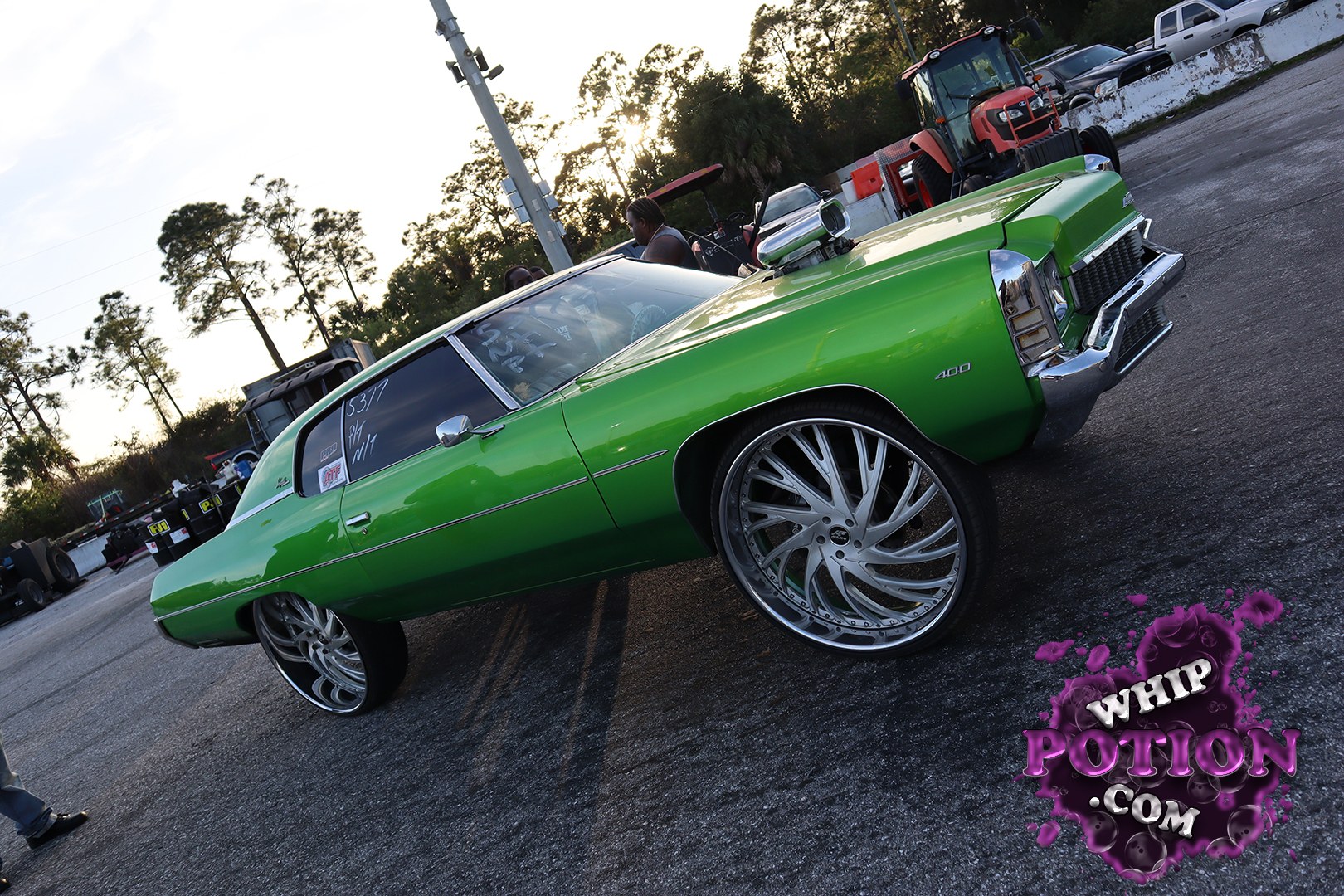 This bright green ’70s-era Pontiac Catalina/Bonneville-style coupe sits low on massive billet wheels, with a chrome hood scoop and clean shaved bodywork giving it a true show-cruiser presence. The long, formal roofline, stacked headlights, and 400 badge fit the big Pontiac look perfectly, while the deep paint and tucked stance make the whole build feel sharp and deliberate.