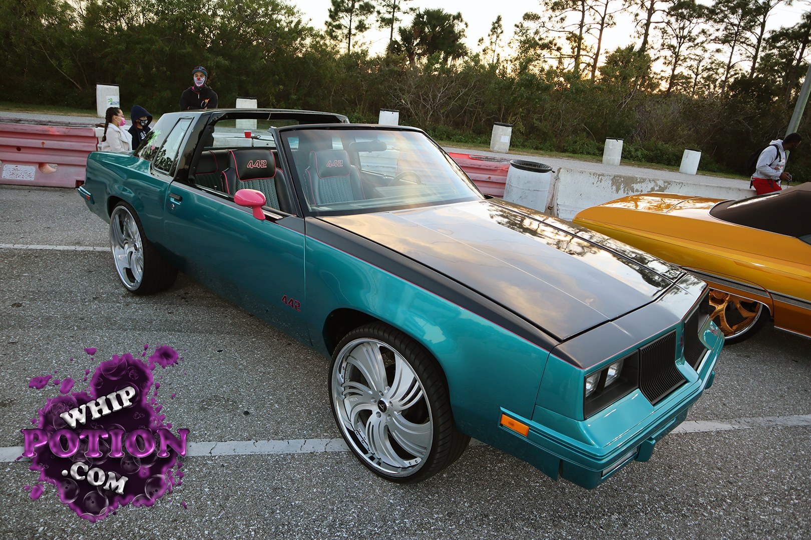 This Buick Regal wears a sharp two-tone teal-and-black setup with 442 badging, a blacked-out hood, and oversized polished wheels that fill the wells nicely. The blacked-out trim and pink accents give it a clean custom edge, while the chopped-looking roofline and bucket-seat interior keep the whole build feeling very much in the street-machine lane.