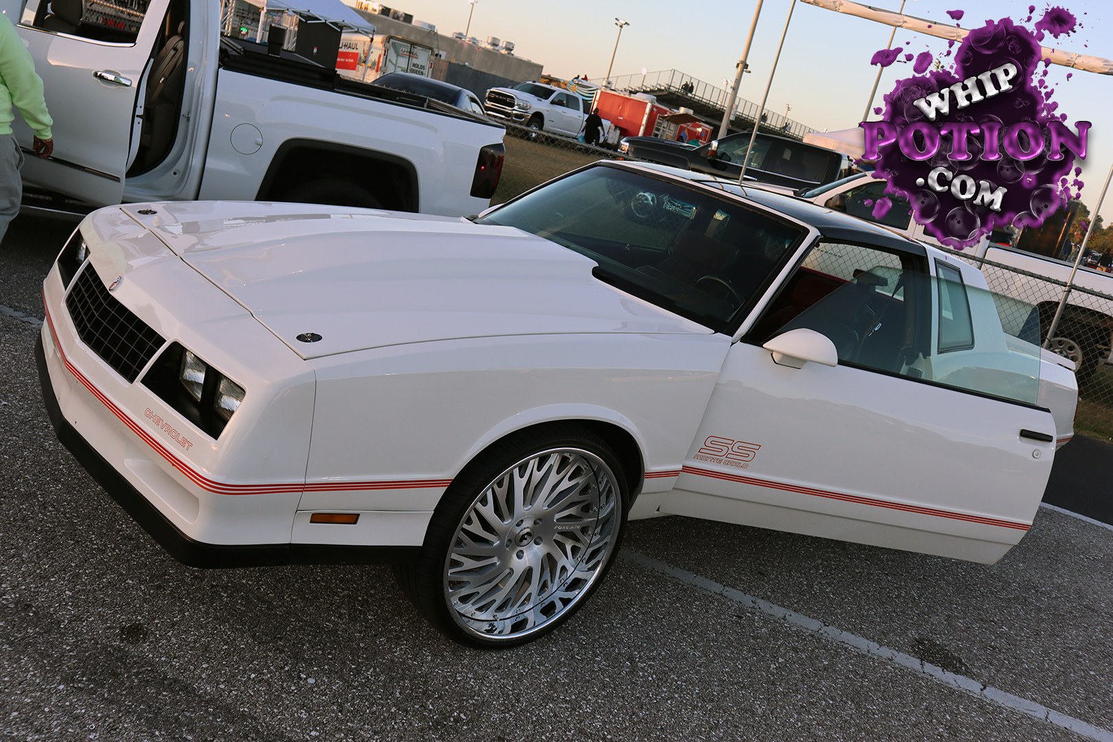 This Chevrolet Monte Carlo SS has the kind of clean, old-school presence that never misses at a car show. The white paint, red pinstriping, and factory-style SS graphics keep it period-correct, while the oversized polished multi-spoke wheels and low, level stance give it a sharper modern edge.
