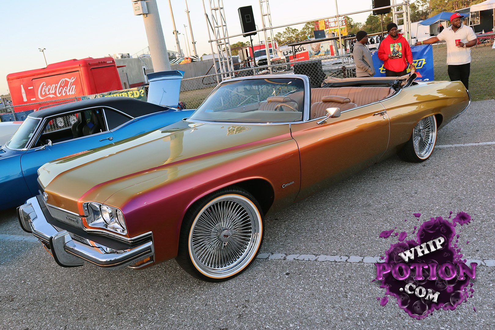A clean Buick Centurion ragtop with a wild candy-style fade from gold to burgundy, sitting on big-wire spokes that fit the old-school feel perfectly. The tan interior is tidy and period-correct, and the chrome nose still brings plenty of class. It’s got that cruise-ready, custom-show presence without losing the muscle-era Buick attitude.