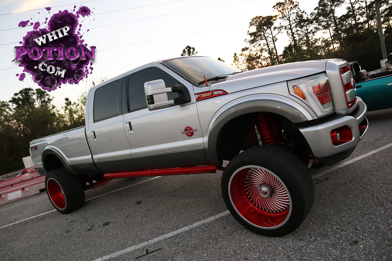 This lifted Ford F-350 Super Duty crew cab is built to make a statement, with silver paint, tinted glass, and a bold red-and-silver wheel package that fills the stretched fenders nicely. The oversized front and rear rollers, red suspension pieces, and clean bodywork give it a proper big-wheel show-truck attitude without losing the heavy-duty Ford presence.