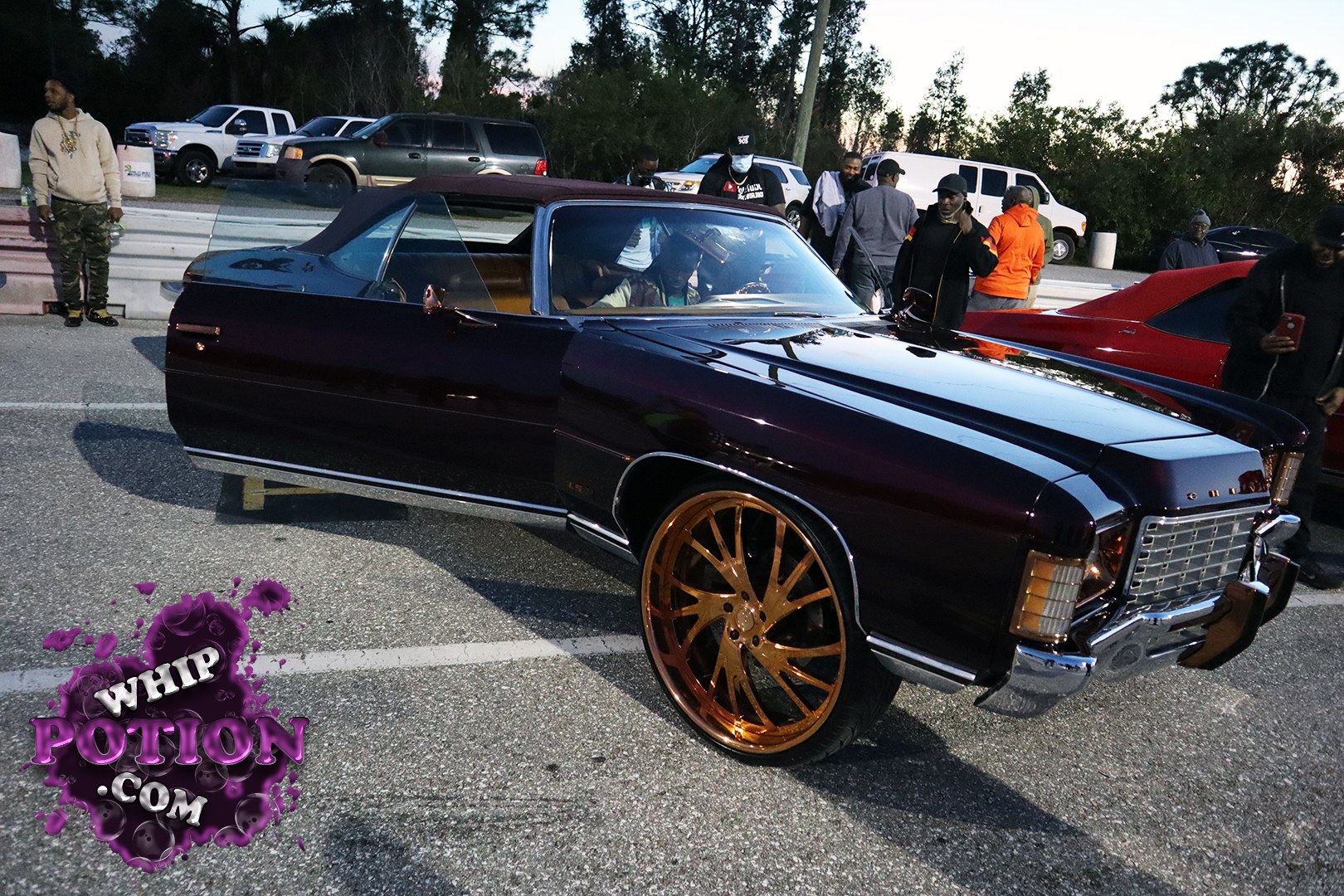 A dark purple Chevrolet Monte Carlo ragtop gets a classy street-cruiser treatment here, with a tan top, deep gloss paint, and huge bronze multi-spoke wheels that fill the arches perfectly. The chrome nose, squared-off body lines, and tidy stance give it that old-school boulevard feel without trying too hard.