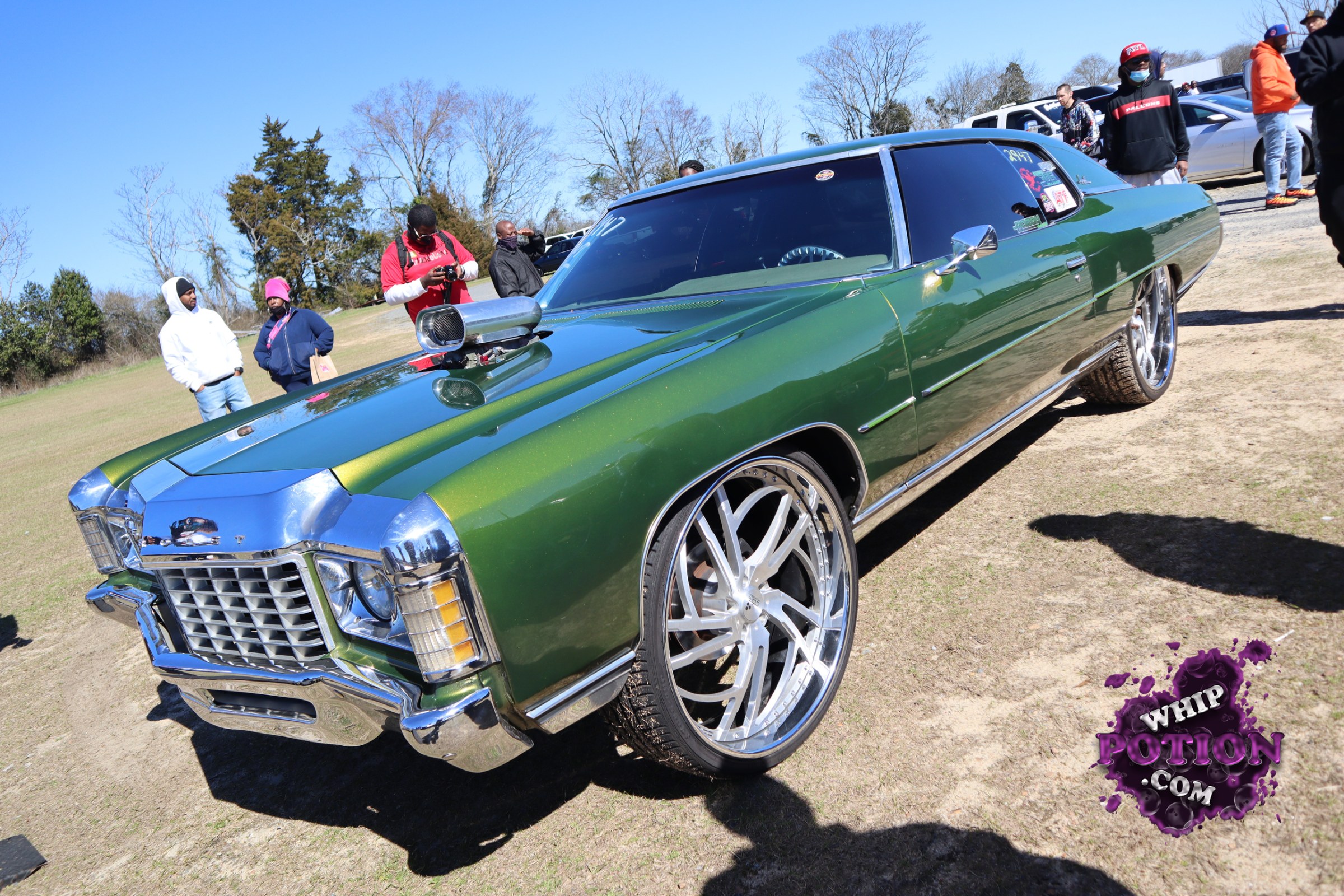 This classic Chevrolet two-door hardtop has been built into a real showpiece, wearing deep metallic green paint with mirror-bright chrome and a big cowl hood scoop up front. The oversized billet-style wheels fill the wells nicely, giving it a bold street-cruiser stance, while the tinted glass and clean body lines keep the whole build looking sharp and deliberate.