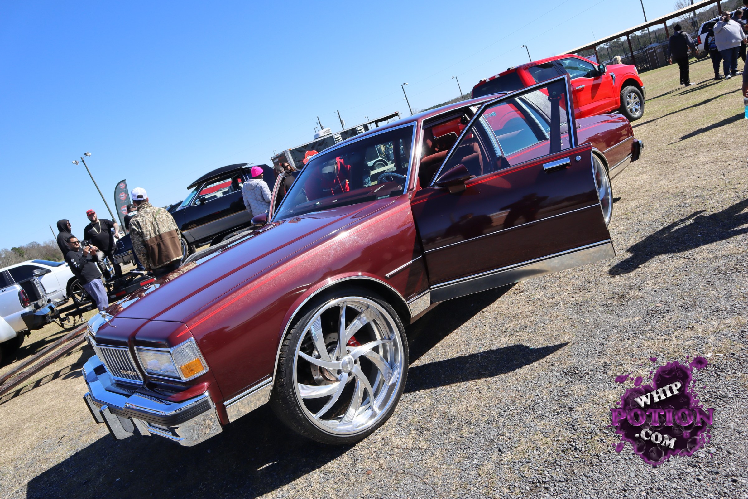 This two-door coupe has classic Olds lines and a proper street-truck attitude, sitting on massive polished five-spoke wheels with a deep-dish look. The burgundy metallic paint and chrome trim pop against the black lower body, and the long doors plus clean, lowered stance give it a well-sorted custom feel without overdoing it.