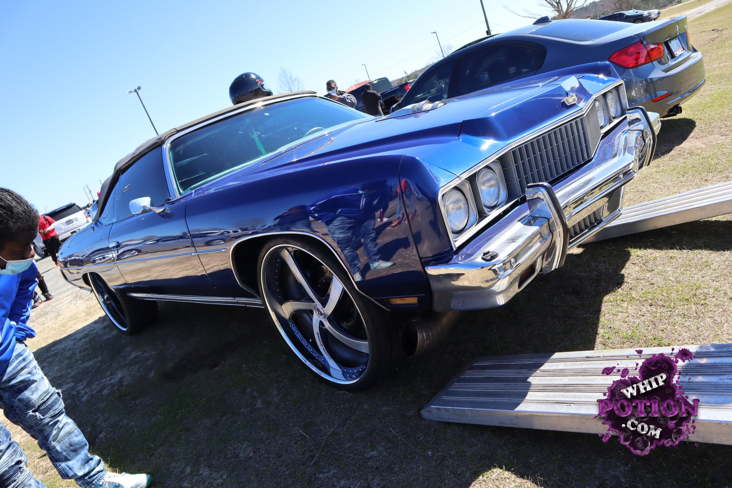 A deep metallic blue Oldsmobile convertible sits low and clean, with a black top, chrome bumpers, and that unmistakable vertical grille giving it real ’70s swagger. The oversized billet-style wheels fill the arches nicely, and the long, squared-off body has been kept sharp without overdoing the mods. It’s got that cruiser look done right.