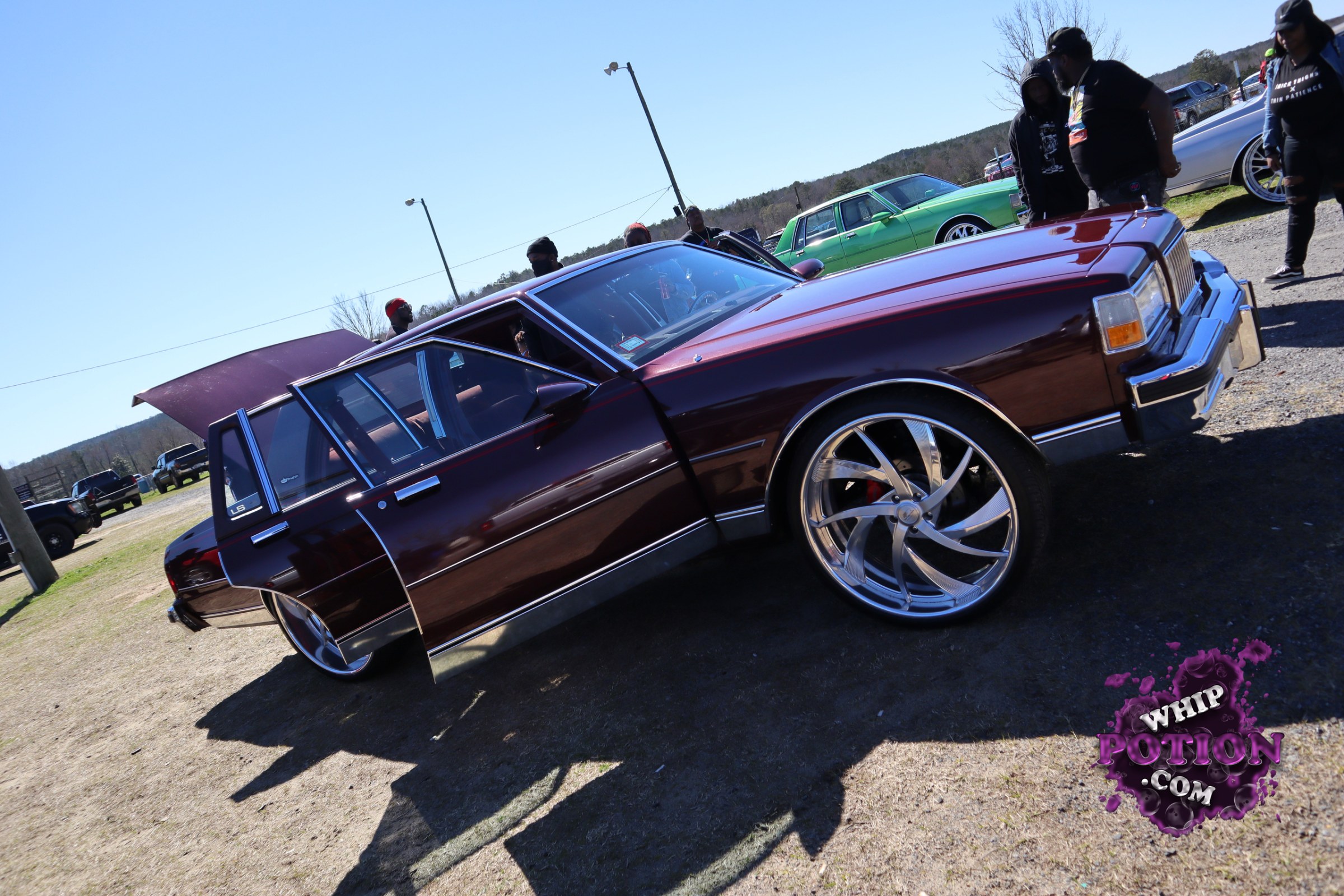 A deep burgundy GM sedan with a clean old-school profile sits on massive chrome five-spokes, the proportions making those big rims look right at home. The long, squared-off nose, vertical grille, and LS badge on the rear window point to a late-’70s Caprice/Impala-era full-size build, laid out with a tasteful drop and plenty of presence.