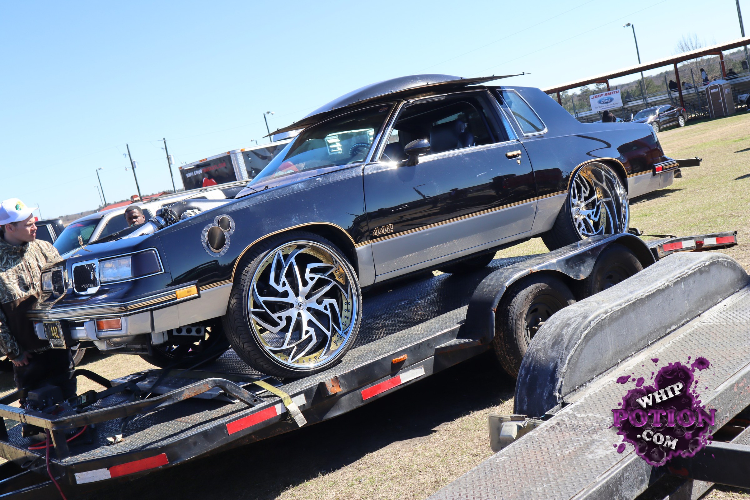 This classic Oldsmobile Cutlass 442 wears a clean black-and-silver two-tone finish with gold pinstriping and a slammed, show-ready stance. The huge billet wheels fill the arches perfectly, and the hood scoop, “442” badging, and side trim keep the muscle-car identity front and center while giving it a sharp custom edge.