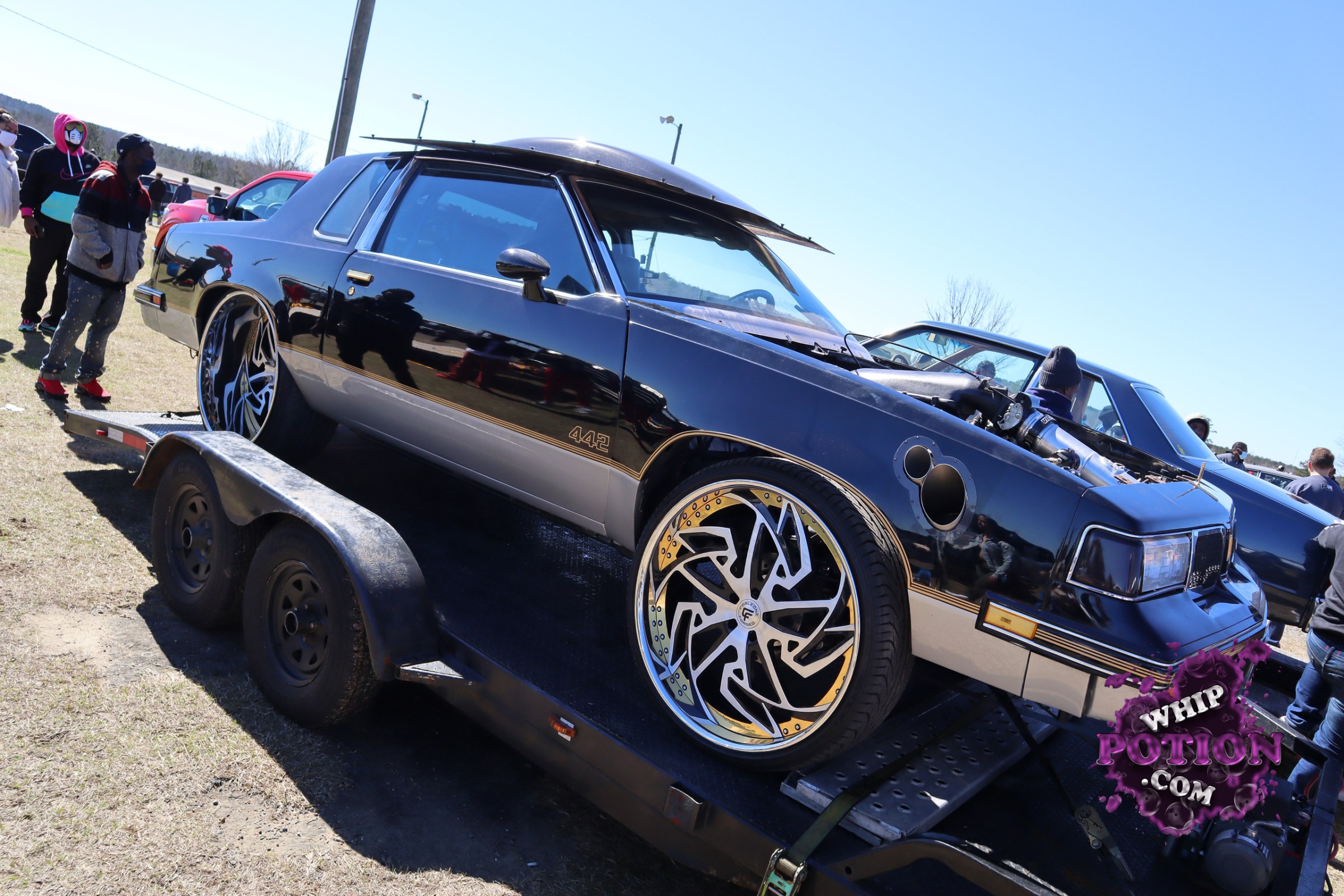 A sharp-looking Oldsmobile Cutlass 442 with a deep black-and-silver two-tone finish, huge staggered billet wheels, and a seriously aggressive stance. The hood’s off, letting the engine bay take center stage, while the clean trim and “442” badging keep the muscle-car identity front and center. It’s the kind of build that mixes old-school swagger with modern show-car attitude.