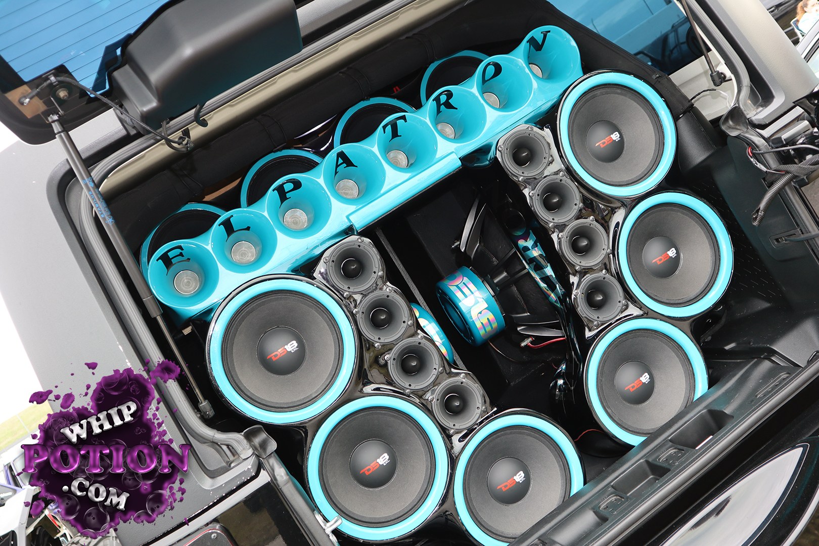 This custom hatchback is built for serious sound, with a tightly packed show-style install filling the cargo area in black and turquoise. Multiple DS18 subwoofers and a stack of mids and tweeters are framed by glossy trim, while the turquoise horn array across the top spells out “EL PATRO.” It’s a clean, aggressive mobile audio setup with real attention to presentation.