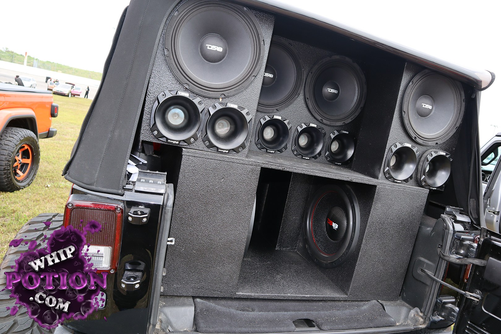 This Jeep Wrangler’s rear cargo area has been turned into a serious soundwall, with a full custom enclosure loaded with DS18 subs and an array of horn-style mids and tweeters. The blacked-out box fills the hatch space cleanly, and the big off-road tire setup out back hints this rig is built to rattle trails and windows alike.