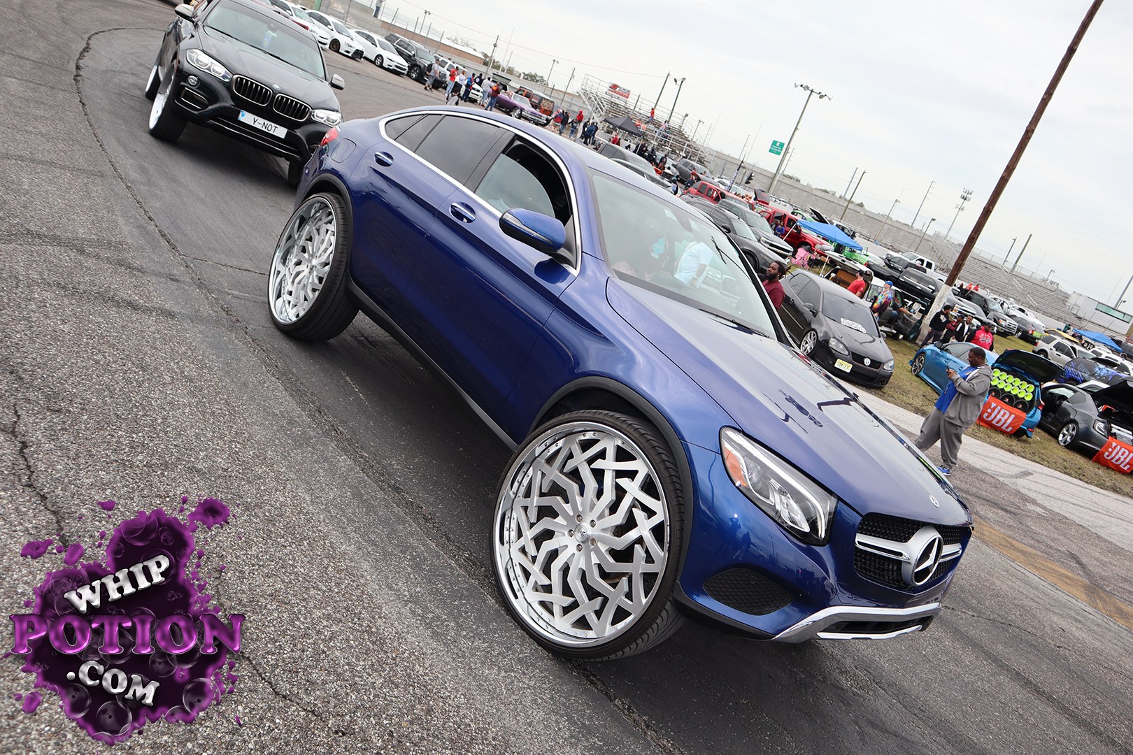 A blue Mercedes-Benz GLC coupe rolls on massive custom multi-piece wheels that fill the arches with real show presence. The deep metallic paint and clean body lines keep it classy, while the low, aggressive stance and tinted glass give it a polished street-truck vibe without overdoing it.
