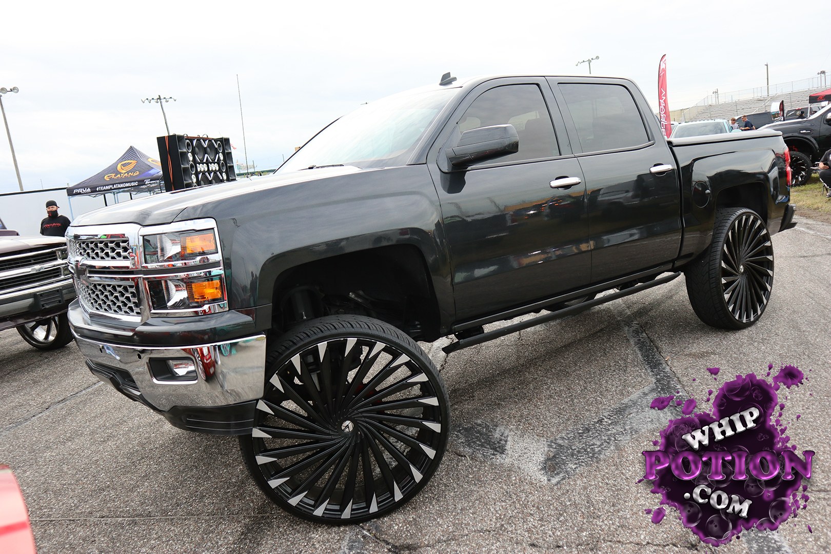 This black Chevrolet Silverado crew cab sits on huge black-and-silver multi-spoke wheels that give it a clean, slammed-show-truck look without overdoing it. The chrome nose and tinted glass keep the vibe sharp, while the long cab and bed proportions make the stance look even more dramatic.