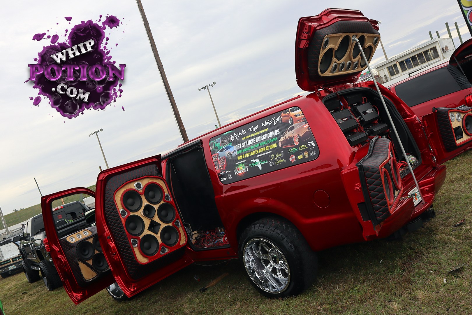 This red Chevy pickup is built for serious sound, with suicide-style rear doors, quilted custom panels, and a full wall of speakers and amps packed into the bed area. The polished billet wheels and chunky tires give it a clean street-truck stance, while the mirrored trim and detailed audio work make it a true showpiece.