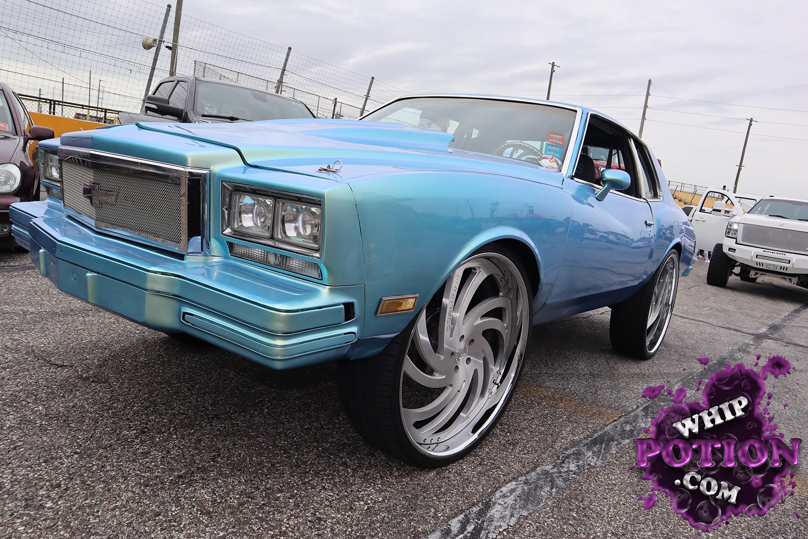 This Chevrolet coupe has a wild custom presence, with that iridescent blue paint flowing over a smoothed nose, mesh grille, and clean bumper treatment. The huge billet-style wheels give it a serious street-machine stance, while the shaved-looking body and tinted glass keep the whole build looking crisp and tailored.