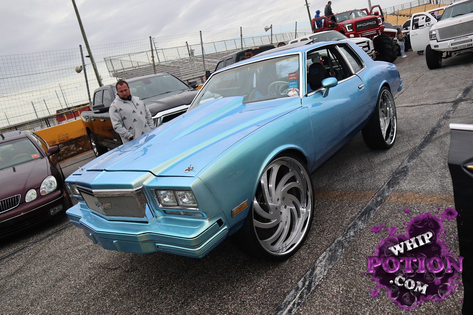 This classic coupe wears a smooth blue-to-teal fade and sits on massive polished billet wheels with a clean, tucked stance. The squared-off nose, quad headlights, and formal roofline give it that late-'70s GM swagger, while the stripped-down interior and dark trim keep the build focused and mean.