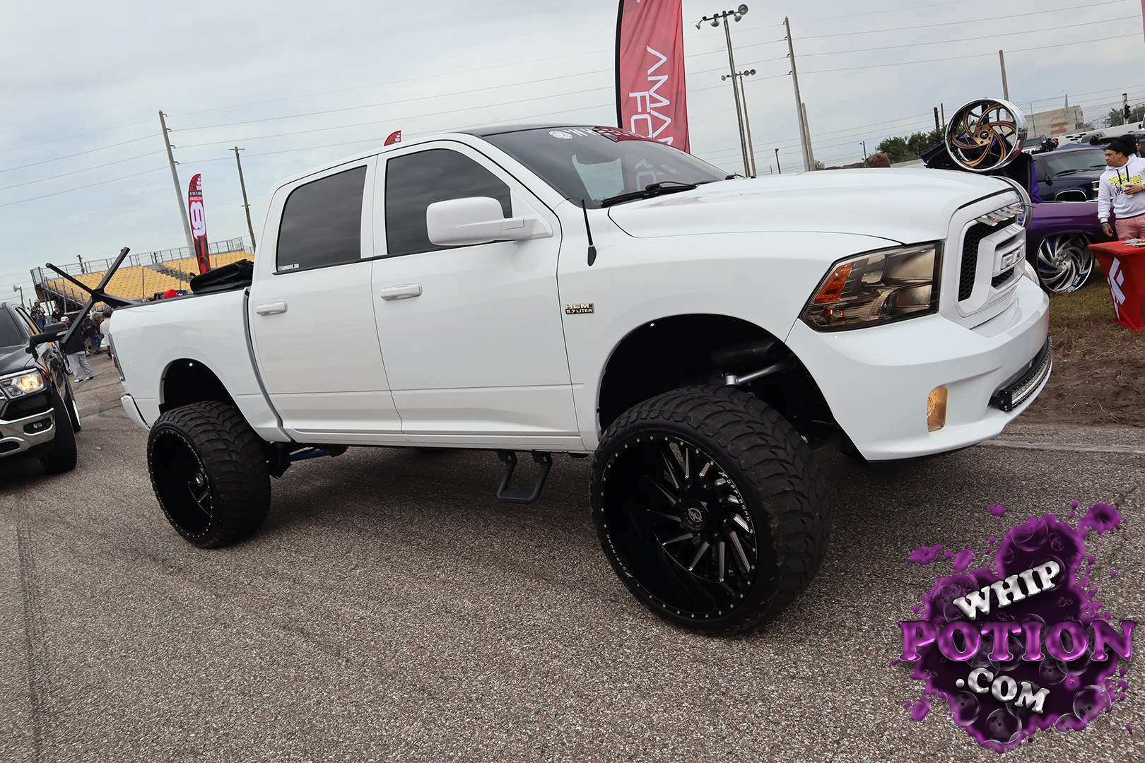 This lifted Ram 1500 crew cab wears a clean white finish, dark tinted glass, and oversized black multi-spoke wheels wrapped in chunky all-terrain tires. The high stance, tucked steps, and simple, monochrome look give it a tough street-truck presence without going overboard. It’s the kind of build that looks ready for both the show lane and the road out.