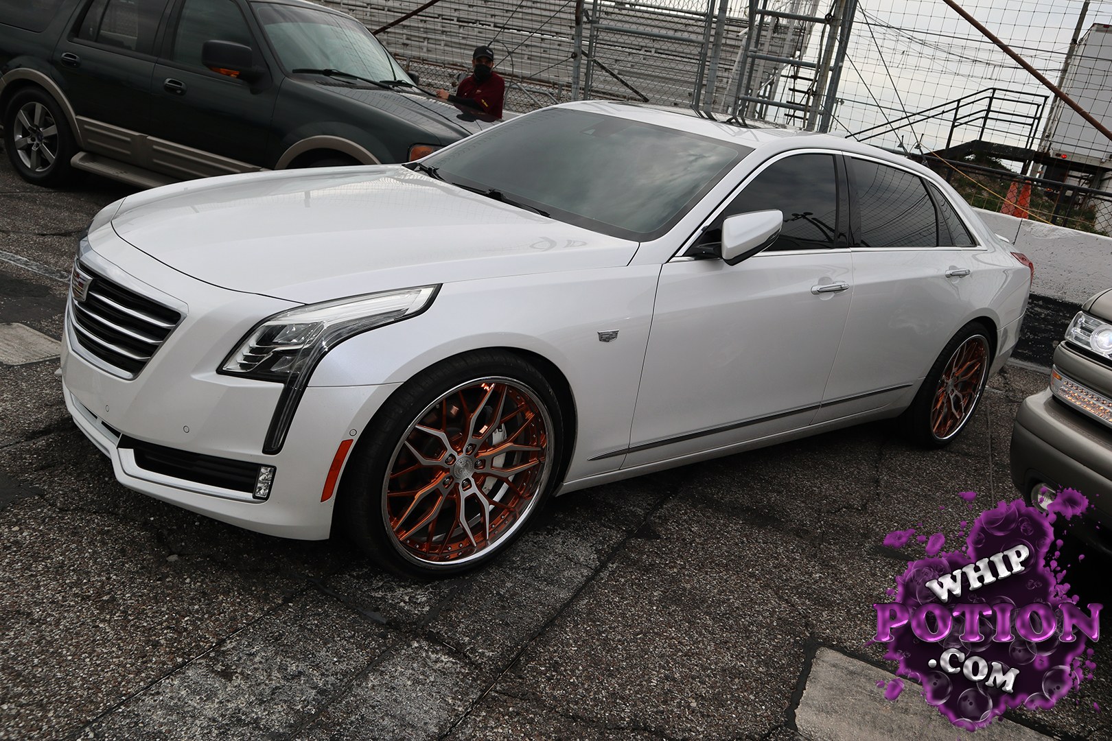 This Cadillac sedan sits clean and classy in pearl white, with a sharp factory body line and a tall chrome grille that keeps the look upscale. The big bronze multi-spoke wheels give it a custom edge, and the dark tint ties the whole build together without overdoing it.
