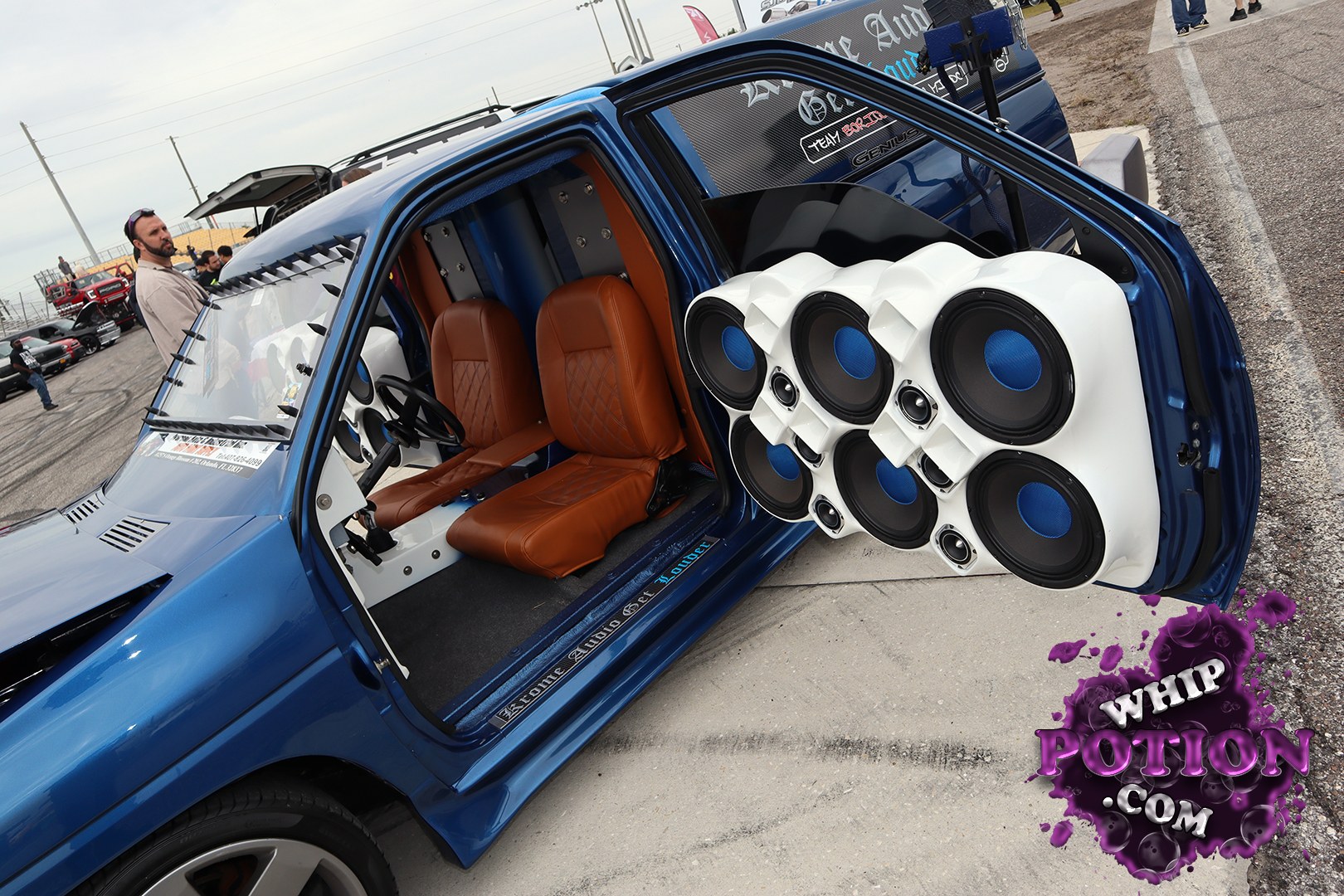 This blue custom pickup is all about the trunk-thumping audio build, with a massive white speaker array mounted in the open door and a clean interior finished in tan leather. The shaved, smoothed bodywork and tinted glass give it a slick show-truck look, while the deep metallic paint and street stance keep it grounded.