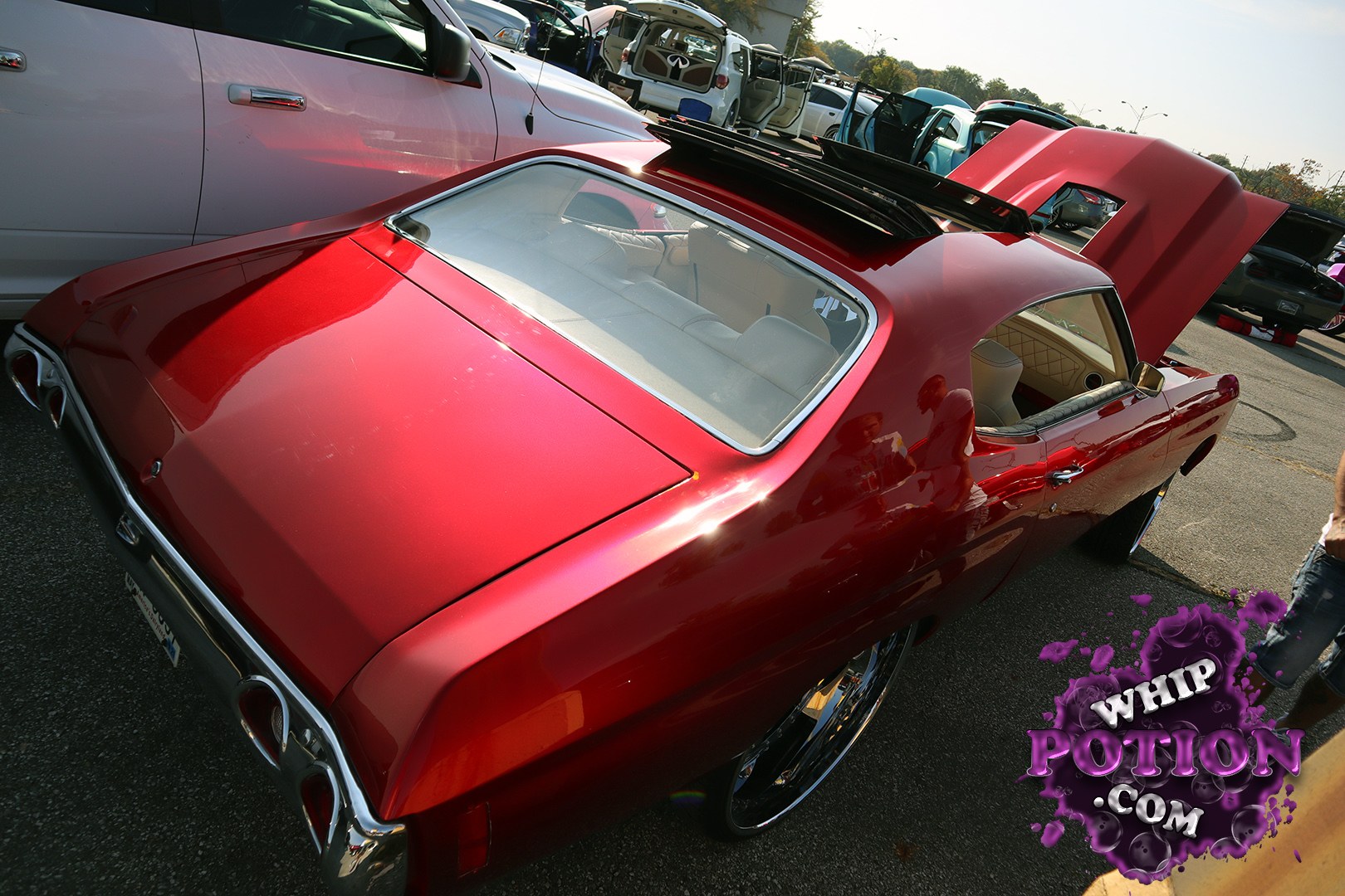 This deep-red classic coupe has a beautifully smoothed custom look, with shaved trim, big chrome rolling stock, and a vivid cream interior that pops through the glass. The proportions and rear treatment give it serious old-school presence, and the open trunk hints at a full custom build without overdoing it.
